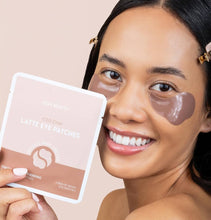 Load image into Gallery viewer, Woman wearing latte eye patches holding a package of eye patches against a beige background